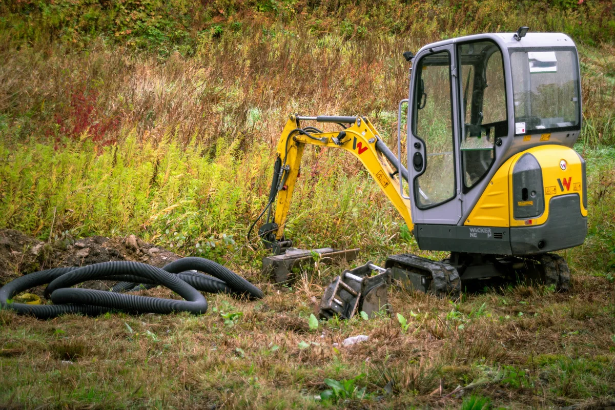 De minikraan tijdens het uitgraven van een tuin